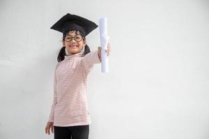 feliz garoto da escola asiática graduado no boné de formatura foto