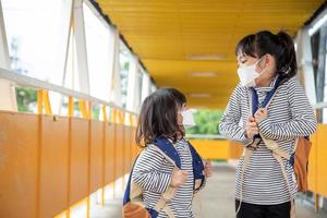 criança em idade escolar usando uma máscara facial durante surto de coronavírus e gripe. menina voltando para a escola após a quarentena e o bloqueio do covid-19. foto