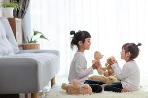 bonitos crianças engraçadas brincando com ursinho de pelúcia em casa foto