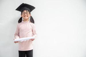 feliz garoto da escola asiática graduado no boné de formatura foto