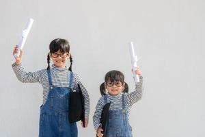 irmãos crianças formatura de menina com boné e diploma sobre branco. foto