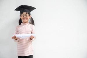 feliz garoto da escola asiática graduado no boné de formatura foto