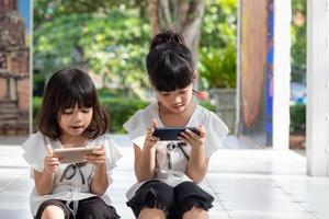 meninas do irmão assistindo seus smartphones em fundo branco. conceito social sobre o vício em pessoas de nova tecnologia foto