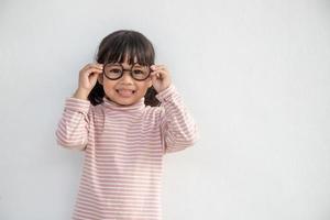 menina asiática engraçada usando óculos em um fundo branco foto