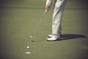 jogador de golfe no putting green batendo bola em um buraco foto