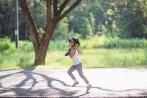 menina criança feliz correndo no parque no verão na natureza. clarão quente da luz solar. pouco asiático está correndo em um parque. esportes ao ar livre e fitness, exercício e aprendizagem de competição para o desenvolvimento infantil. foto