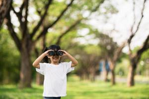 menina criança feliz brincando com binóculos. explorar e conceito de aventura foto