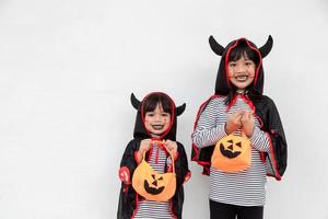 feliz dia das bruxas duas crianças em trajes de halloween e com abóboras em fundo branco foto