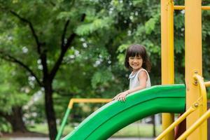 garota feliz na área de playground de slides foto