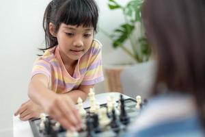 irmãzinha jogando xadrez em casa. foto