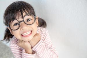 menina asiática engraçada usando óculos em um fundo branco foto