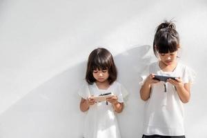 meninas do irmão assistindo seus smartphones em fundo branco. conceito social sobre o vício em pessoas de nova tecnologia foto