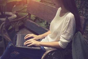 linda jovem asiática trabalhando em uma cafeteria com um laptop. mulher freelancer conectando-se à internet via computador. foto