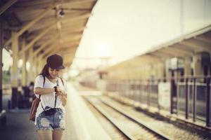 mulher viajante andando e espera trem na plataforma ferroviária foto