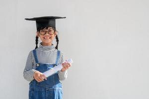 feliz garoto da escola asiática graduado no boné de formatura foto