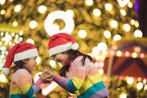 feliz natal crianças felizes com um presente mágico em casa perto da árvore de natal foto