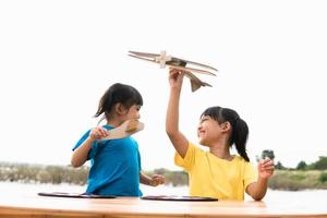 duas crianças brincando com avião de brinquedo de papelão no parque durante o dia. conceito de jogo feliz. criança se divertindo ao ar livre. foto