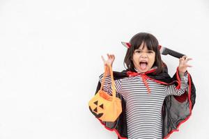 conceito engraçado de criança de halloween, menina bonita com fantasia fantasma de halloween assustador ele segurando fantasma de abóbora laranja na mão, sobre fundo branco foto