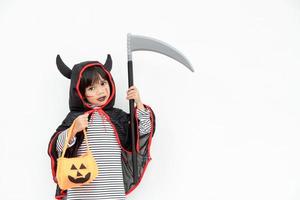 menina de crianças usando misterioso vestido de halloween segurando uma foice e uma abóbora assustadora. foto