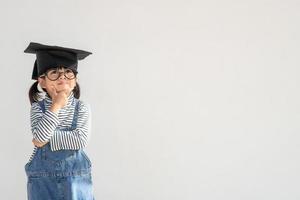 feliz estudante de escola asiática graduado pensando com boné de formatura foto