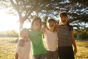 grupo de amigos do jardim de infância se abraçam e se divertem sorrindo com o pôr do sol foto