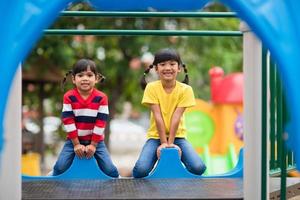irmãos de meninas bonitinhas se divertindo no playground ao ar livre em dia ensolarado de verão foto