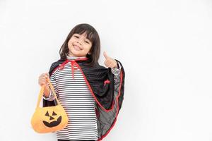 conceito engraçado de criança de halloween, menina bonita com fantasia fantasma de halloween assustador ele segurando fantasma de abóbora laranja na mão, sobre fundo branco foto