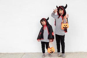 feliz dia das bruxas duas crianças em trajes de halloween e com abóboras em fundo branco foto