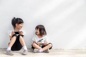 meninas irmãs gostam de usar smartphones em fundo branco, o conceito de tecnologia de comunicação e pessoas foto