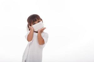 menina asiática feliz usando máscara higiênica para prevenir infecção por vírus corona poluição do ar pm2.5.on fundo branco foto
