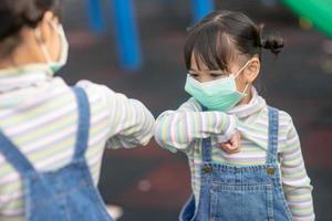 novo estilo de vida normal, conceito de distanciamento social. crianças felizes usando máscaras faciais se divertindo no playground protegem o coronavírus covid-19, foto