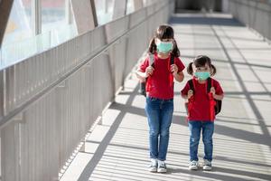 imagem de retrato de irmãos de crianças asiáticas bonitos usando uma máscara facial e pegue uma mochila escolar. volta para a escola e as crianças. infância foto