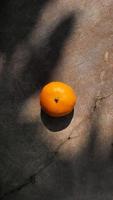 uma tangerina com piso de cimento exposto nas sombras foto