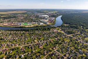 vista panorâmica aérea da aldeia verde com casas, celeiros e estrada de cascalho na floresta foto