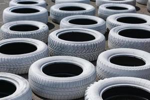 pneus de carros usados velhos, pintados de branco brilhante e instalados na pista de corrida para segurança foto