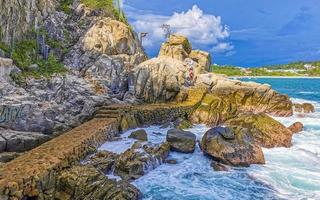 belas ondas de surfista rochas falésias na praia puerto escondido méxico. foto