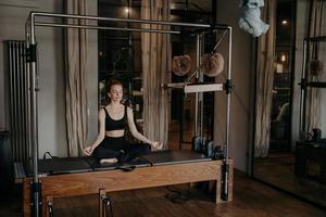 jovem em forma sentada em posição de lótus na mesa de trapézio foto