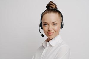 linda consultora de call center na camisa branca no fone de ouvido preto foto