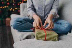 foto recortada de mulher abrindo caixa de presente de natal embrulhada em casa durante as férias de inverno