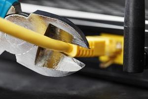 rasgando e cortando com cortadores de fio azul a conexão de rede do fio amarelo da conexão com a internet. foto