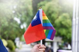 bandeira do arco-íris e bandeira nacional de taiwan segurando na mão, foco suave e seletivo, conceito para celebração do lgbtq plus no mês do orgulho em todo o mundo. foto