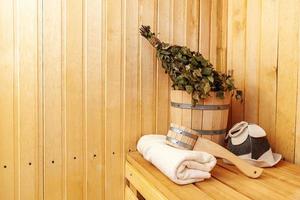 detalhes do interior sauna finlandesa sala de vapor com sauna tradicional acessórios bacia vassoura de bétula colher feltro toalha de chapéu. conceito de spa de balneário russo antigo tradicional. relaxe o conceito de banho da vila do país. foto