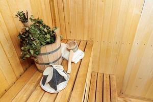 detalhes do interior sauna finlandesa sala de vapor com sauna tradicional acessórios bacia vassoura de bétula colher feltro toalha de chapéu. conceito de spa de balneário russo antigo tradicional. relaxe o conceito de banho da vila do país. foto