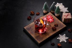 vinho tinto quente de natal com especiarias e frutas em uma mesa de concreto foto