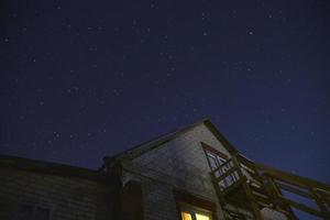 o céu estrelado e os telhados das casas. astrofotografia em uma vila com casas. foto