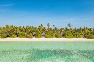paisagem aérea perfeita, villas privadas de resort tropical de luxo. bela praia da ilha, palmeiras, céu ensolarado. incrível vista de olhos de pássaro nas maldivas, costa paradisíaca. turismo exótico, relaxar natureza mar foto