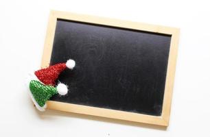 chapéu de papai noel de decorações de natal no fundo do quadro-negro de madeira foto