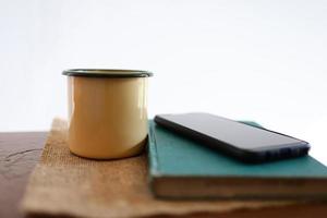 canecas de café amarelas, telefones e livros na mesa de madeira dentro de casa. foto