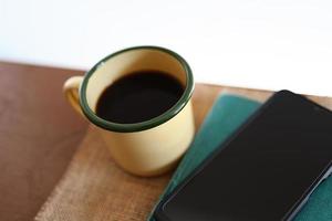 canecas de café amarelas, telefones e livros na mesa de madeira dentro de casa. foto