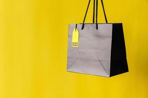 saco de compras preto com preço amarelo com fundo amarelo para o conceito de venda de compras de sexta-feira negra. foto